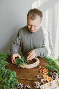 A man at home makes a christmas wreath from fresh spruce branches. decorating your home 