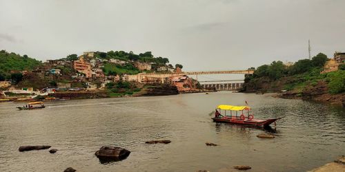 Boat moored in river by buildings against sky