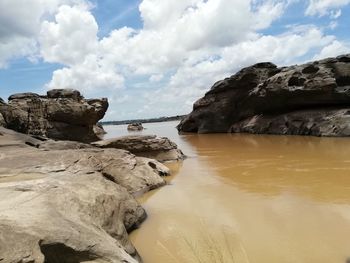 Rock formations on shore against sky