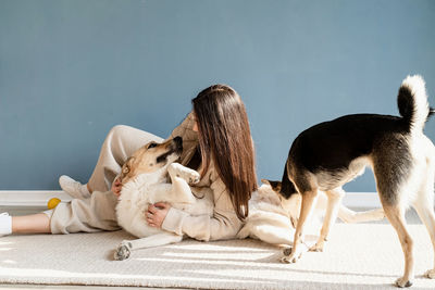 Beautiful brunette woman with playful mixed breed dog, embracing and having fun at home