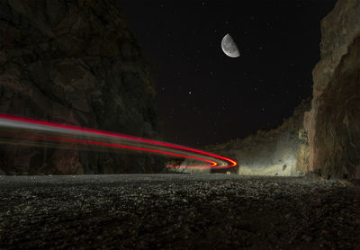 Light trails on field against sky at night