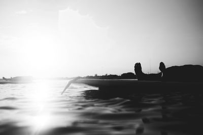 Silhouette woman by sea against sky during sunset