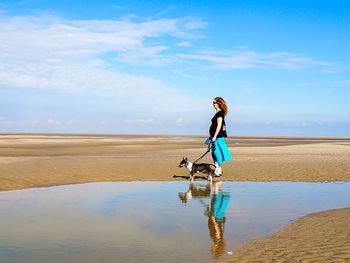 Full length of a woman jumping on landscape against blue sky