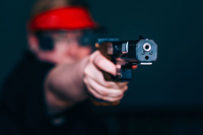 Close-up of woman aiming gun against black background
