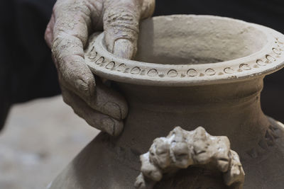 Cropped hand of potter holding earthenware in workshop