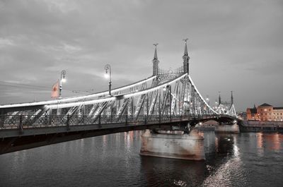 Liberty bridge over danube river in city against cloudy sky