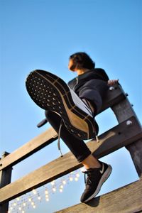 Low angle view of woman against clear blue sky