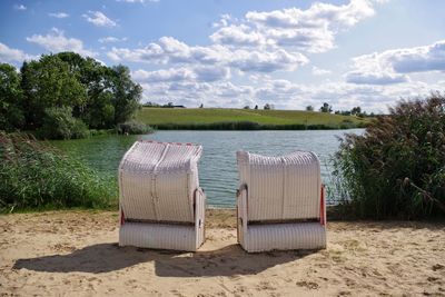 Hooded chairs on beach against sky