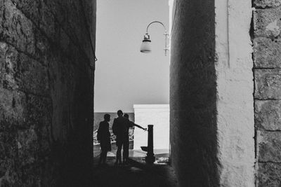 People on street by wall against building