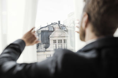 Rear view of businessman looking at building through hotel window