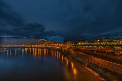 Illuminated bridge over river against sky at night