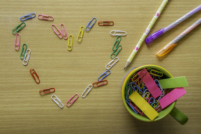 Directly above paper clips forming heart shape by school supplies on table