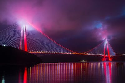 Illuminated suspension bridge over river at night