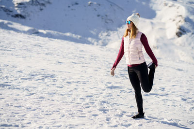 Full length of woman skiing on snow covered landscape