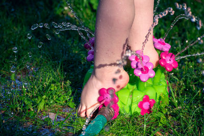 Low section of woman with pink flower on field