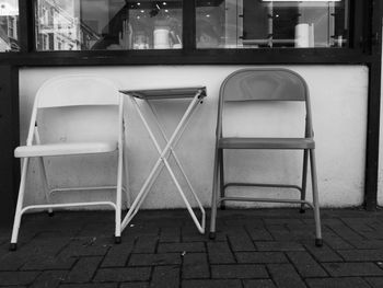 Empty chairs by table at sidewalk cafe