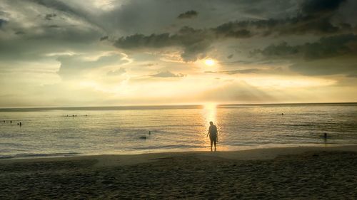 Silhouette man standing on beach against sky during sunset