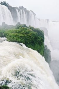 Scenic view of waterfall by sea against sky