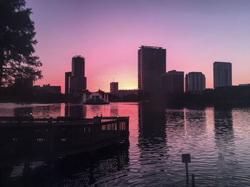 River by buildings against sky during sunset
