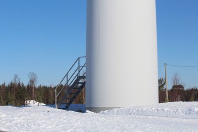 Low angle view of snow covered field against clear blue sky