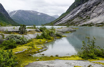 Scenic view of river by mountains against sky