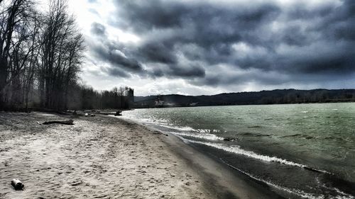 Scenic view of beach against storm clouds