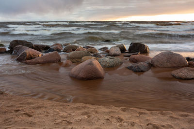 Rocks on beach against sky during sunset