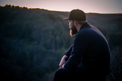 Side view of young man looking at mountain during sunset