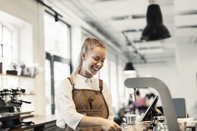 Happy female barista preparing coffee at cafe