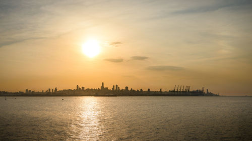 Panoramic view of sea and buildings against sky during sunset