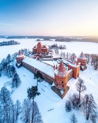 High angle view of snow covered plants by building against sky