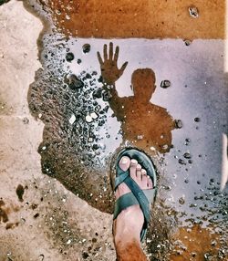 Low section of man standing on puddle