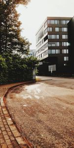 Empty road by building against sky