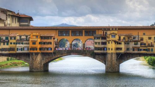Bridge over river in city against sky