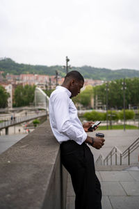 Rear view of man photographing while standing against sky