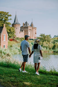 Rear view of couple walking in front of building