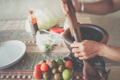 Cropped hands with mortar and pestle at table