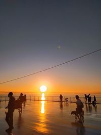 Silhouette people playing on beach against sky during sunset