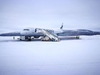 Airplane on snow covered landscape against sky