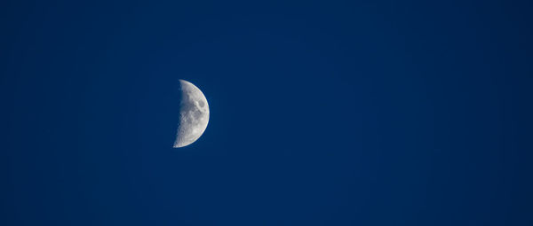 Low angle view of moon against clear blue sky