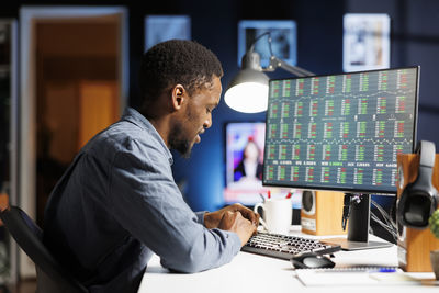 Side view of businessman using laptop at office