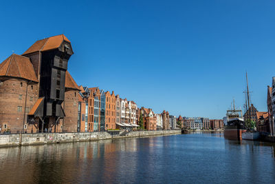 Buildings at waterfront against blue sky
