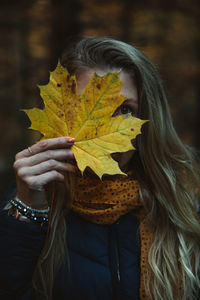 Portrait of woman holding maple leaves during autumn