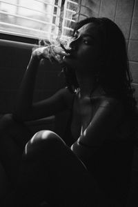 Young woman smoking cigarette while sitting at home