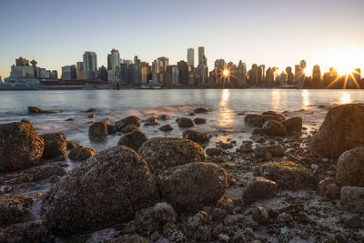 Scenic view of sea by buildings against sky during sunset