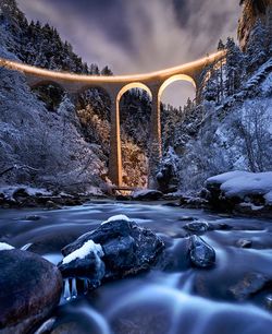 Bridge over river against sky during winter