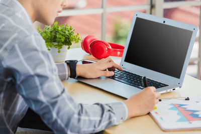 Midsection of businessman using laptop on table