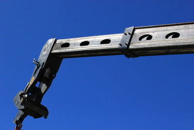 Low angle view of crane against clear blue sky