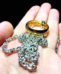 Close-up of human hand holding ring against black background