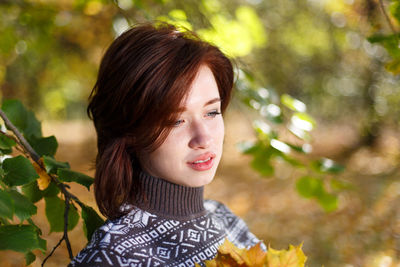 Outdoor portrait of young caucasian woman in knitted sweater posing on